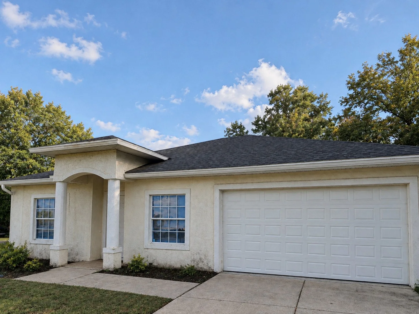 Before: Single-storey home with a stucco exterior, arched entry with columns and white garage door