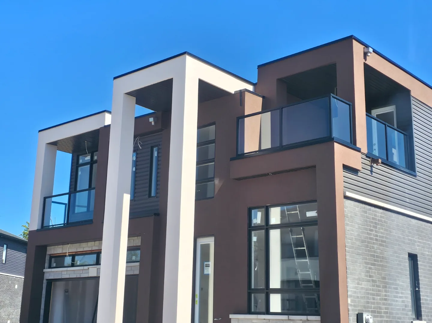 New two-story modern home for Centennial Homes with cream and brown EIFS columns, balconies and stucco walls